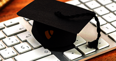 A black graduation cap with the TYPO3 logo placed on a white computer keyboard.