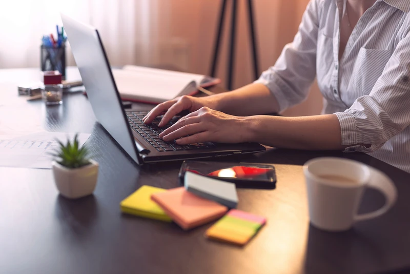 DE Detailansicht einer Frau am Laptop mit kreativen Arbeitsutensilien. EN Detailed view of a woman at a laptop with creative work utensils.