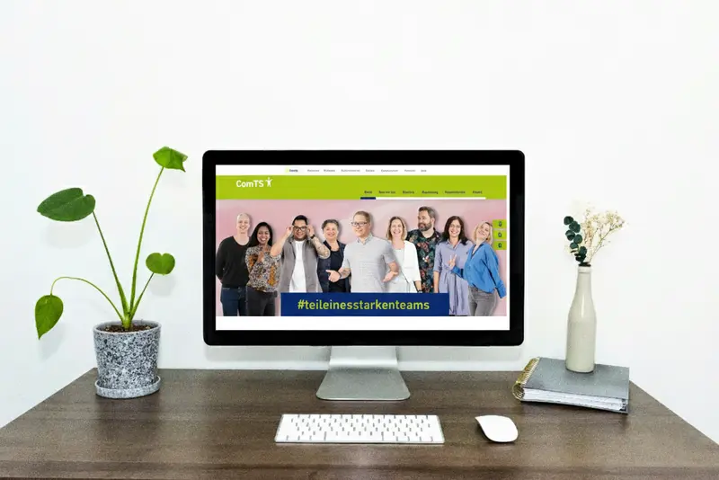 ComTS Employer-Branding-Kampagne Laptop zeigt die neue ComTS Website mit dem Slogan „#teileinesstarkenteams“ und einer Gruppe von Mitarbeitenden