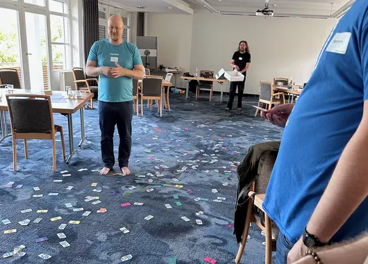 Pluscamp 2023 - agile coach Thorsten in masses of cards from the agile card game Lucky Salmon on the carpeted floor